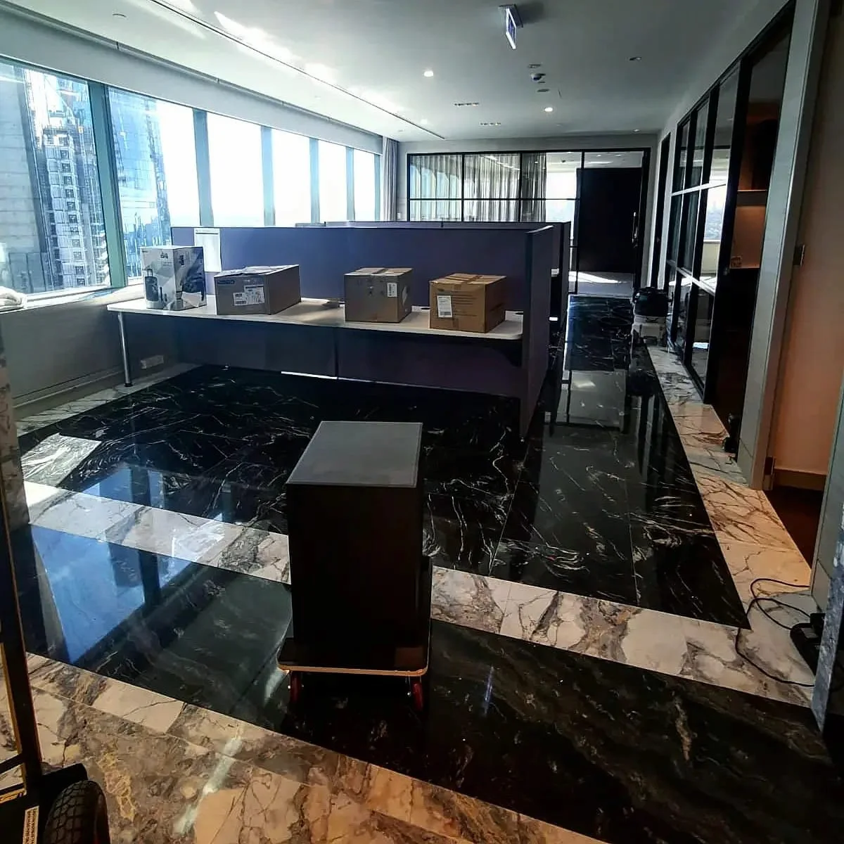 Packed moving boxes and equipment in a modern corporate office with marble floors, ready for a professional commercial relocation by Atlantis Removals in Newcastle.