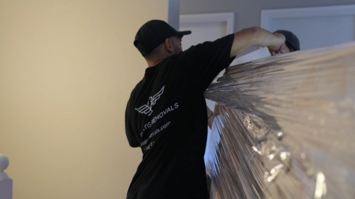 Trained Atlantis Removals professional carefully shrink-wrapping large furniture to protect it during a Newcastle relocation.